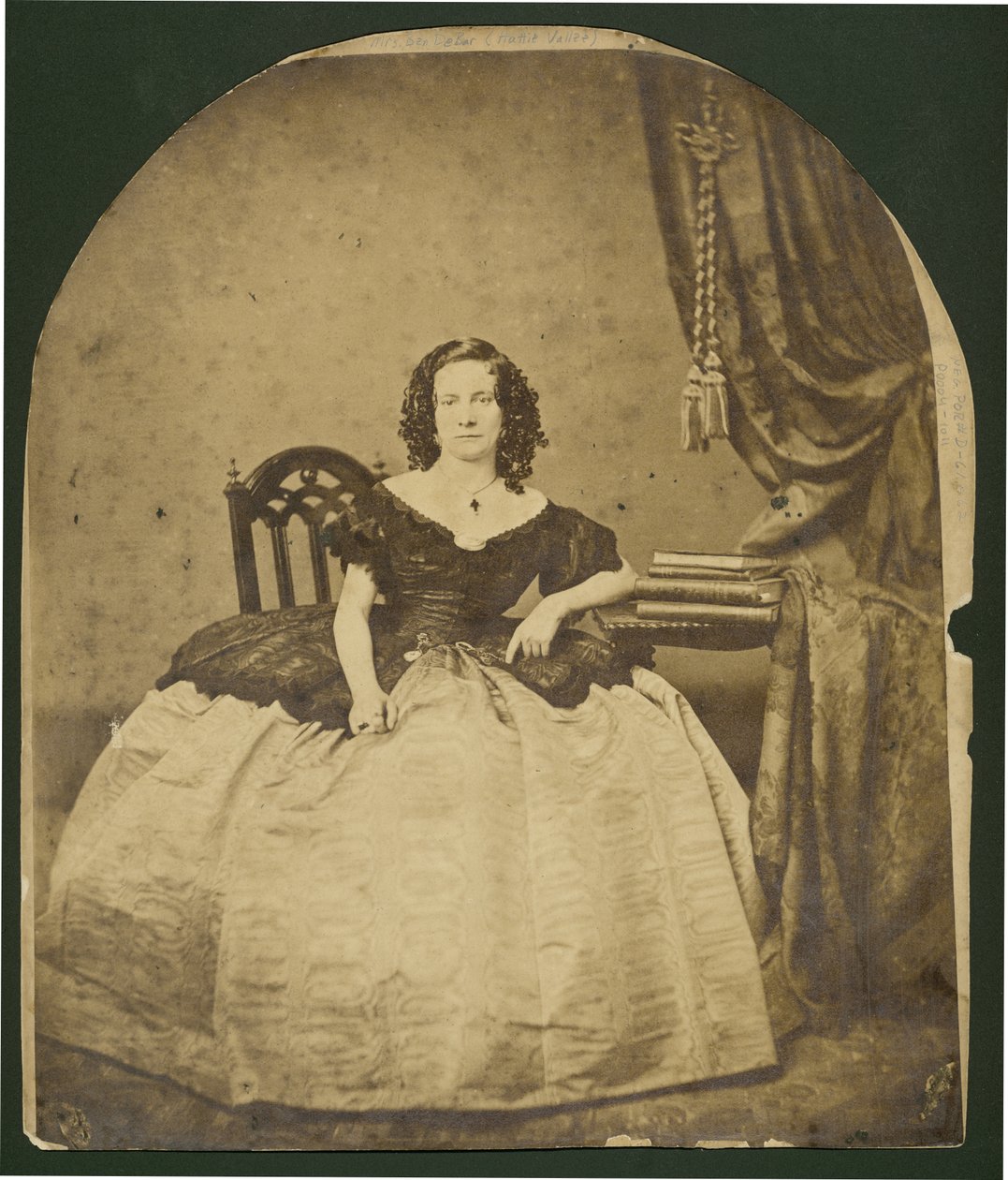 Full-length portrait of a seated, curly haired woman in a dress with a full skirt av Unknown
