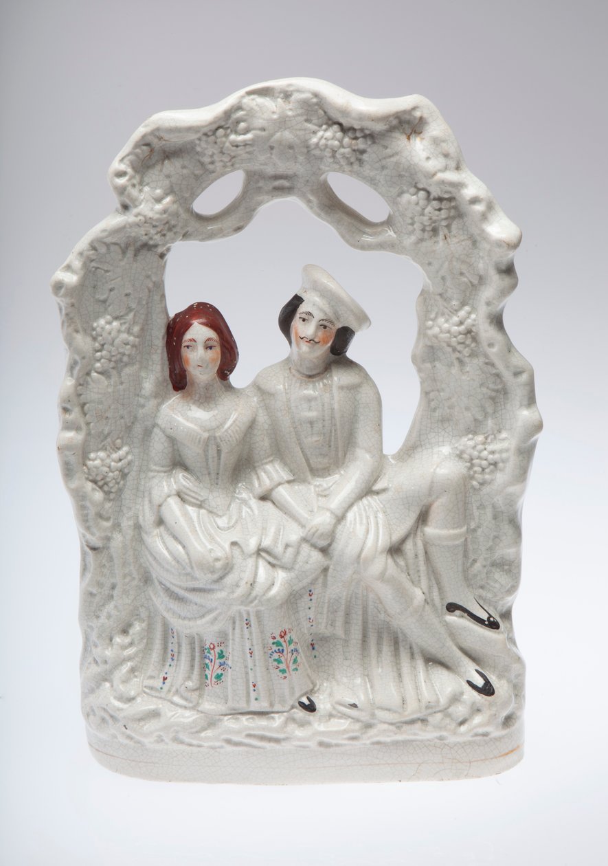Staffordshire ceramic figurine of a couple seated holding hands. Possibly a wedding scene av Unknown