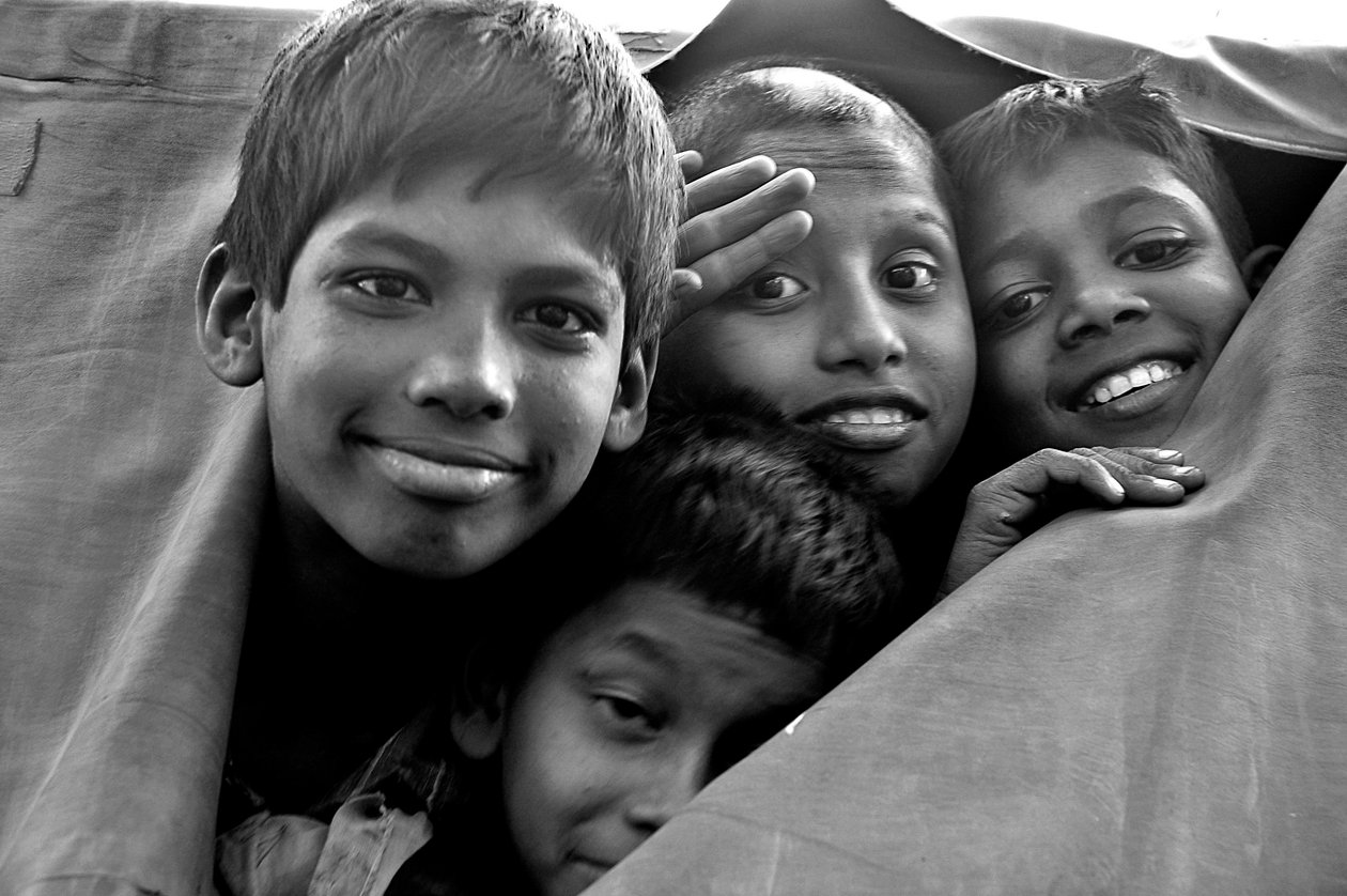 Utblottade barn tittar genom en trasig duk av en polisbil i staden Dhaka, Bangladesh. 26 november 2006. av Unknown