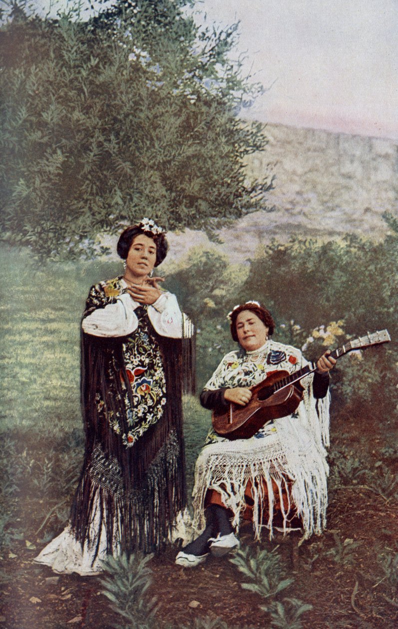Spanien. Medan hennes kamrat spelar gitarr klappar den unga flickan lätt i händerna. De flesta spanska dansare föredrar denna form av ackompanjemang. 1920 av Unknown