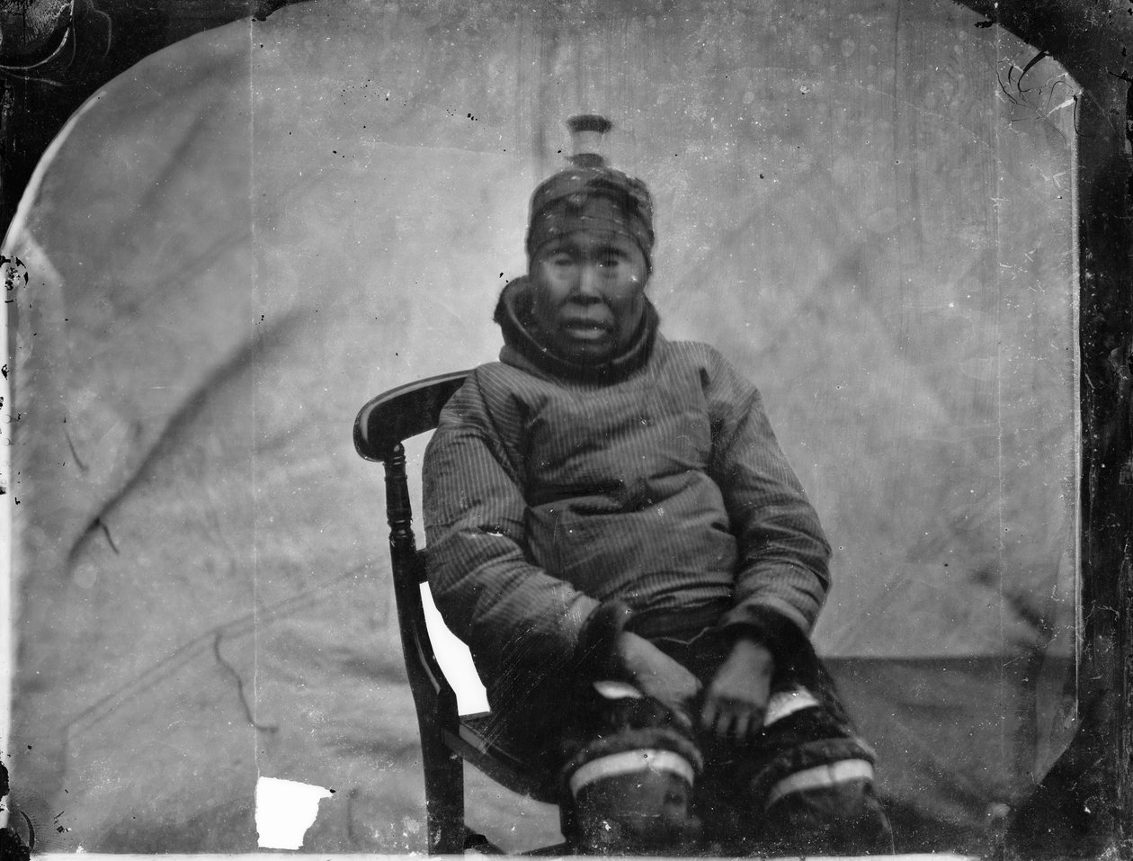 En äldre inuk-kvinna sitter i en stol av Admiral Edward Augustus Inglefield