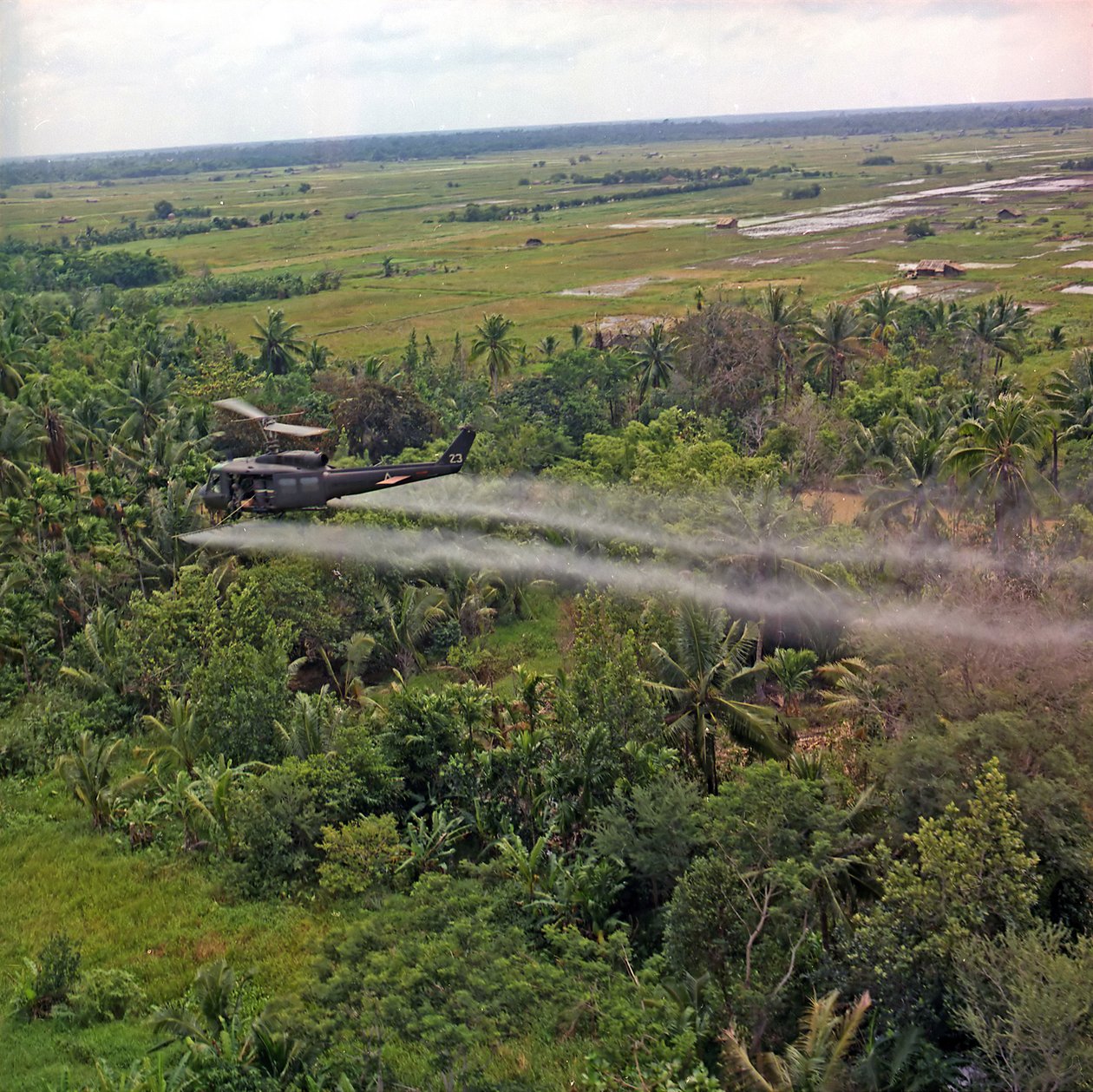 En UH-1D-helikopter från 336th Aviation Company sprejar ett avlövande medel på ett tätt djungelområde i Mekongdeltat, 26 juli 1969 av American Photographer