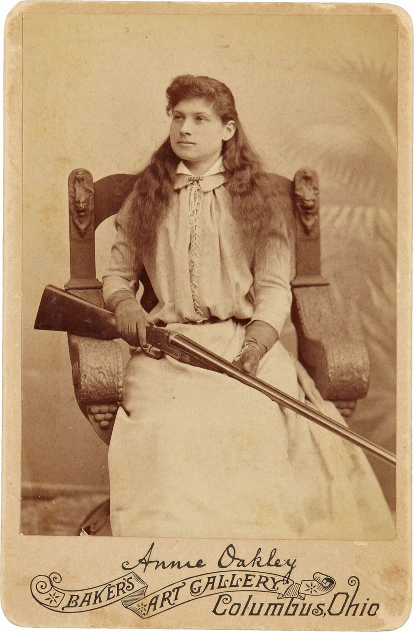 Annie Oakley: Annie Oakley:. Här sitter den legendariska skarpskytten ganska ödmjukt i en massiv stol i renässansstil, ett hagelgevär vilande i hennes knä. Hennes ömtåliga feminina drag och flytande hår motverkar hennes robusta utomhusbild ©Buyenlarge/UIG/ av American Photographer