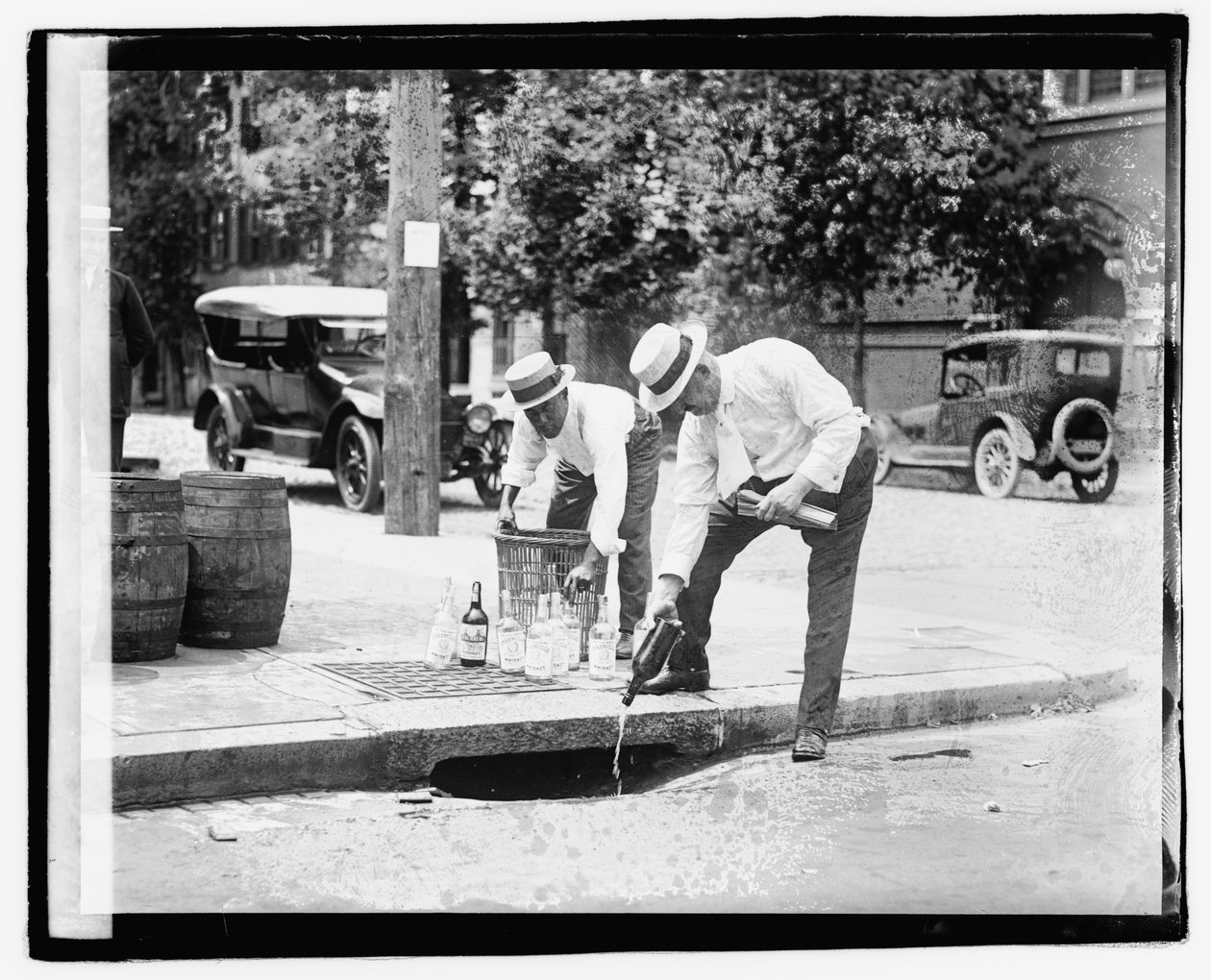 Två män som häller sprit i stormavloppet, 8 juli 1921 (s/v foto) av American Photographer