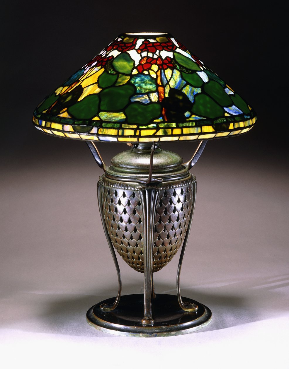 En bordslampa "Geranium" med konisk skärm och urnfot i brons med nät med fiskfjällsmönster, 1900-tal av American School