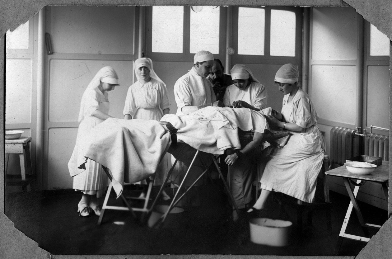 Första världskriget 1914-1918: läkare och sjuksköterskor vid röda korset (Therese Pavillou? ) som behandlar en soldats sår som sover i kloroform i lägret Couville i Manche, Basse-Normandie (Lagre Normandie), Frankrike. Anonym fotografering av Anonymous Anonymous