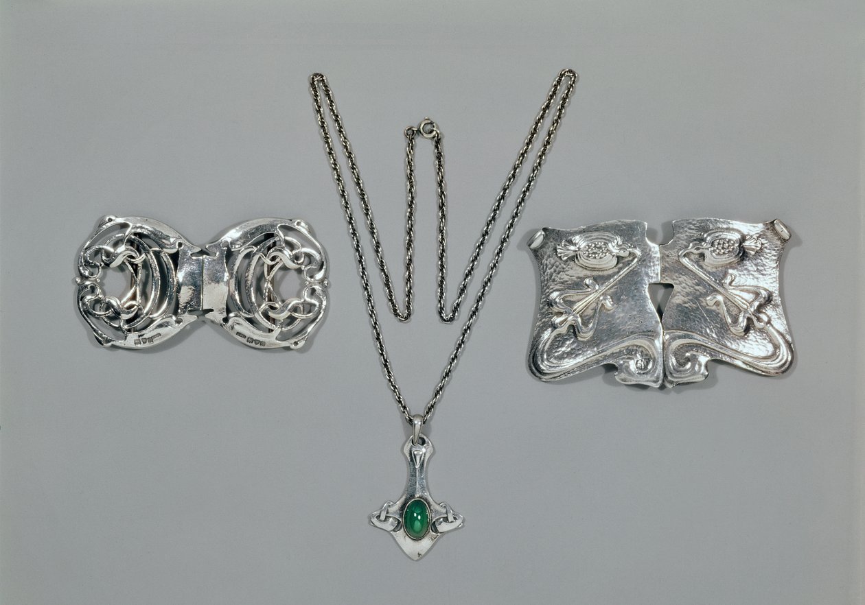 Silversmycken designade för Liberty. Vänster till höger: Midjelås med sammanflätad keltisk design, 1904. Hänge och kedja med cabochonskuren krysopras. Midjelås med repouse-design på hamrad av Archibald Knox