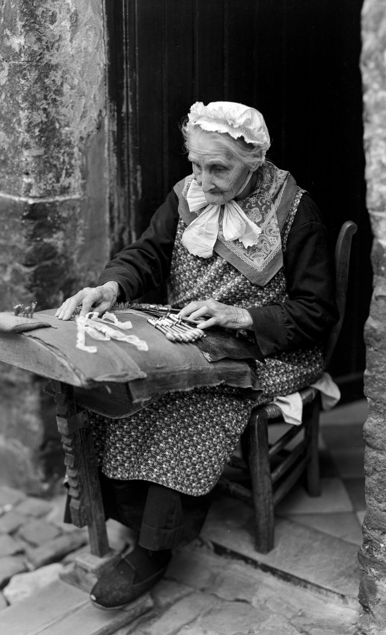 Lacemaker, en äldre kvinna, i Brygge sitter vid sin dörröppning medan hon gör spetsribbor... av B. Anthony Stewart