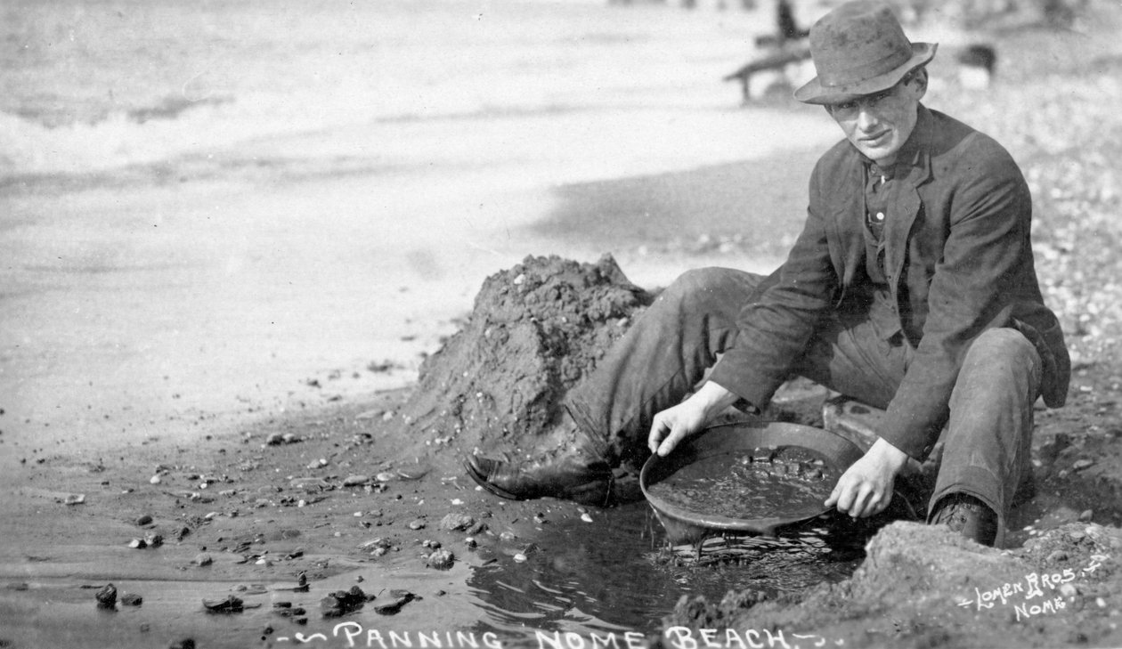 Man panorerar guld på stranden, Nome, Alaska, ca 1910 (s/v foto) av Brothers Lomen