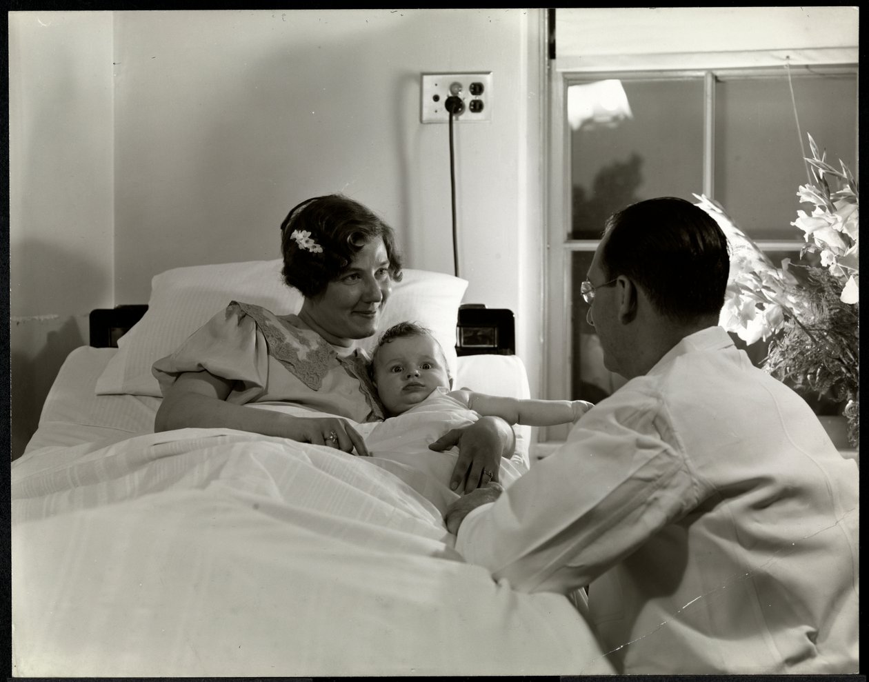 En mor och ett barn i en sjukhussäng, New York, ca 1937 (silvergelatintryck) av Byron Company