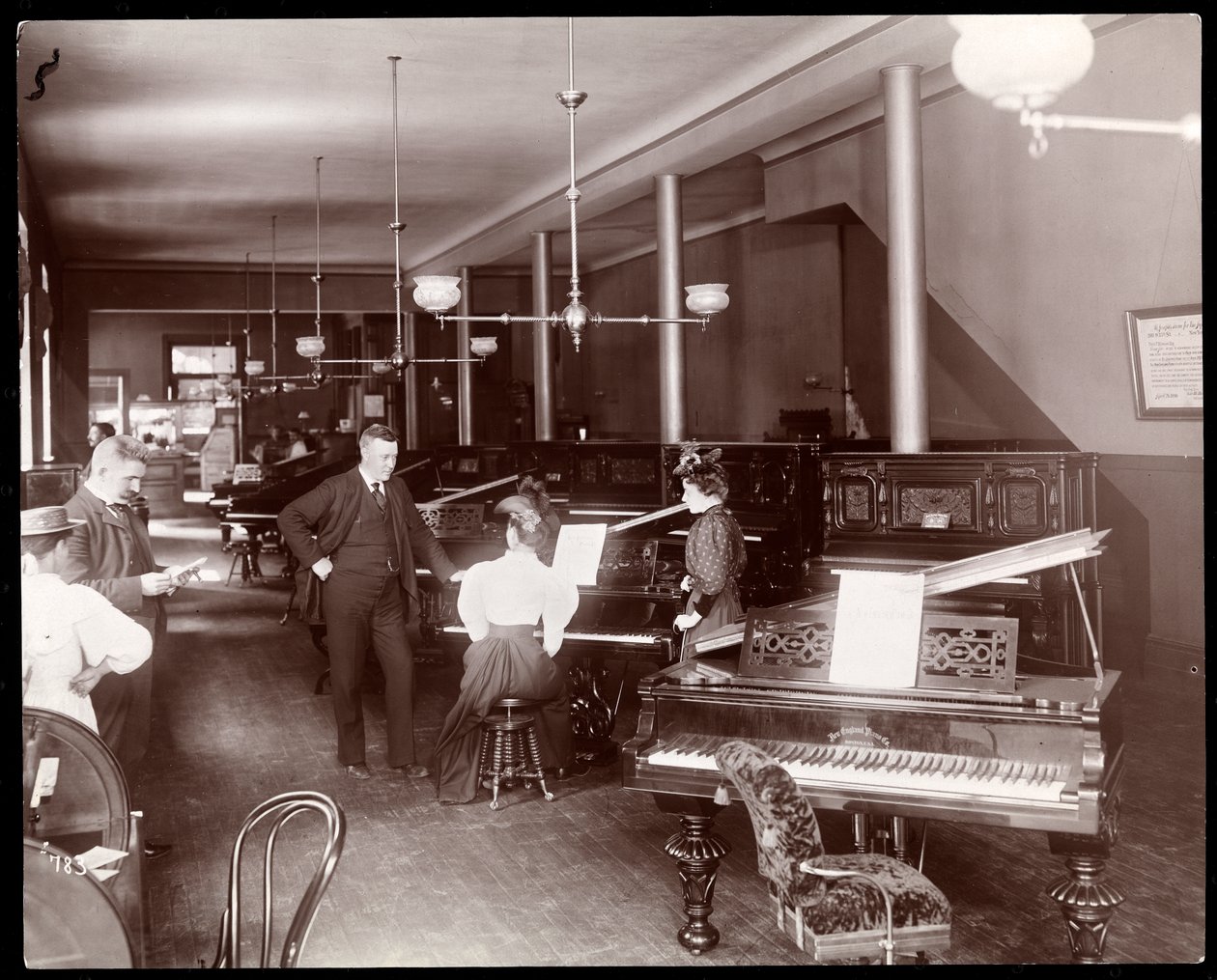 New England Piano Co.:s utställningsrum, 1895 (silvergelatintryck) av Byron Company