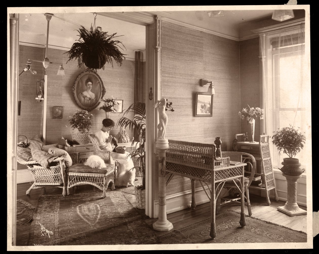 En kvinna som utför ett nålarbete i ett vardagsrum, 1914 eller 1915 (silvergelatintryck) av Byron Company
