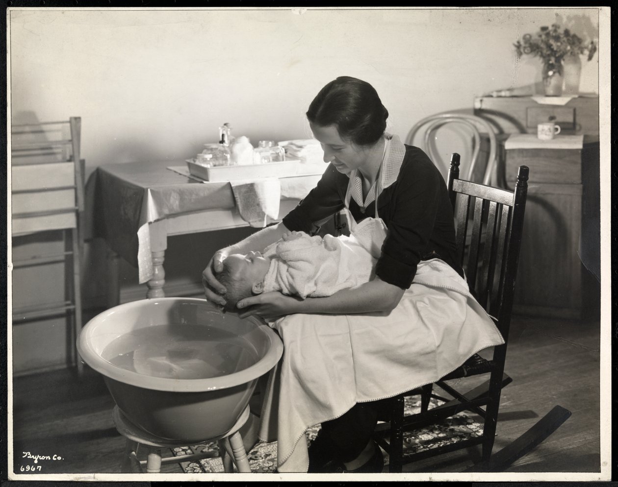 En kvinna som tvättar ett barns huvud på Maternity Center Association på 211 East 57th Street, New York, 1934 (silvergelatintryck) av Byron Company