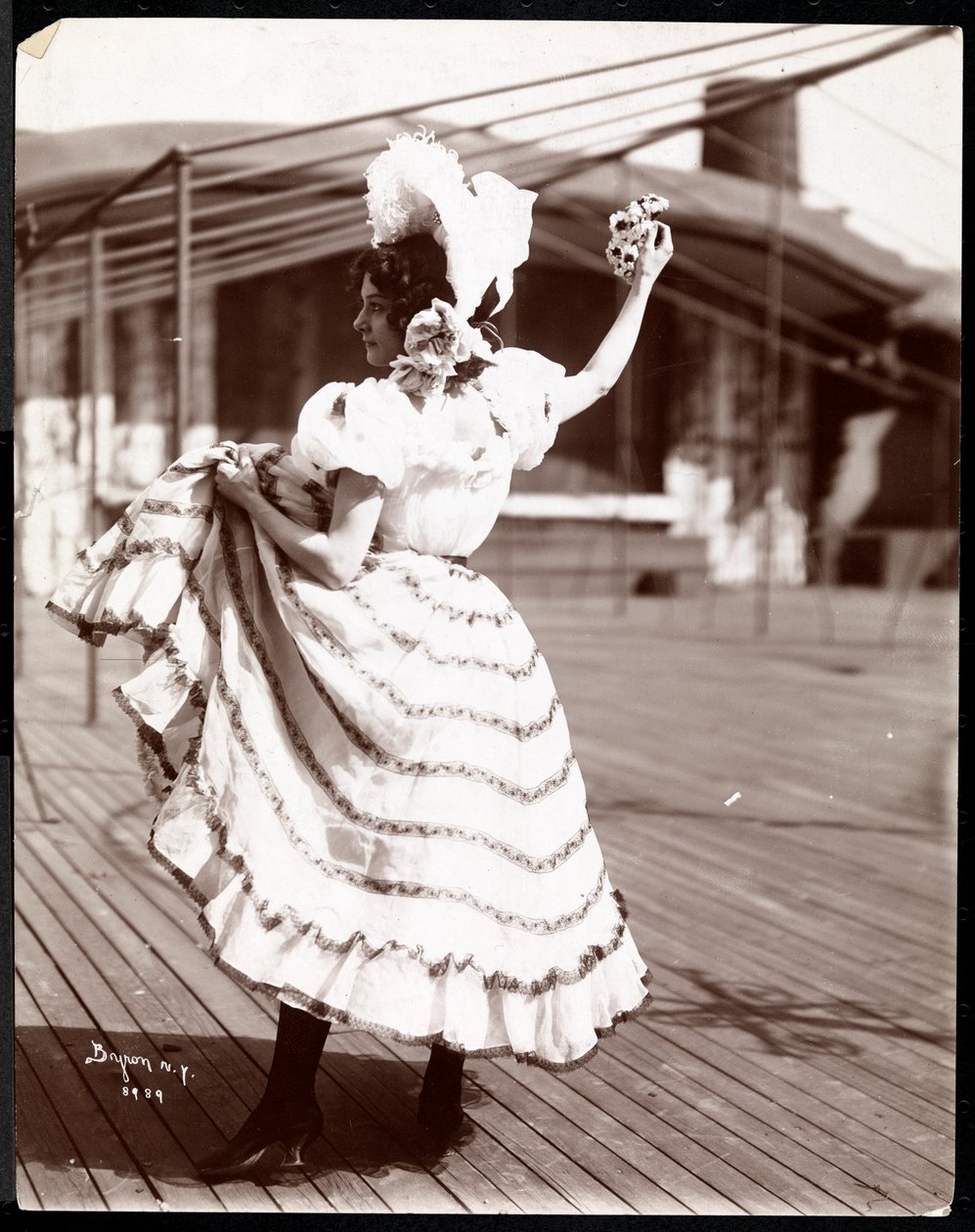 En skådespelerska i kostym repeterar på taket till vad som troligen är New York Theatre, New York, 1900 (silvergelatintryck). av Byron Company