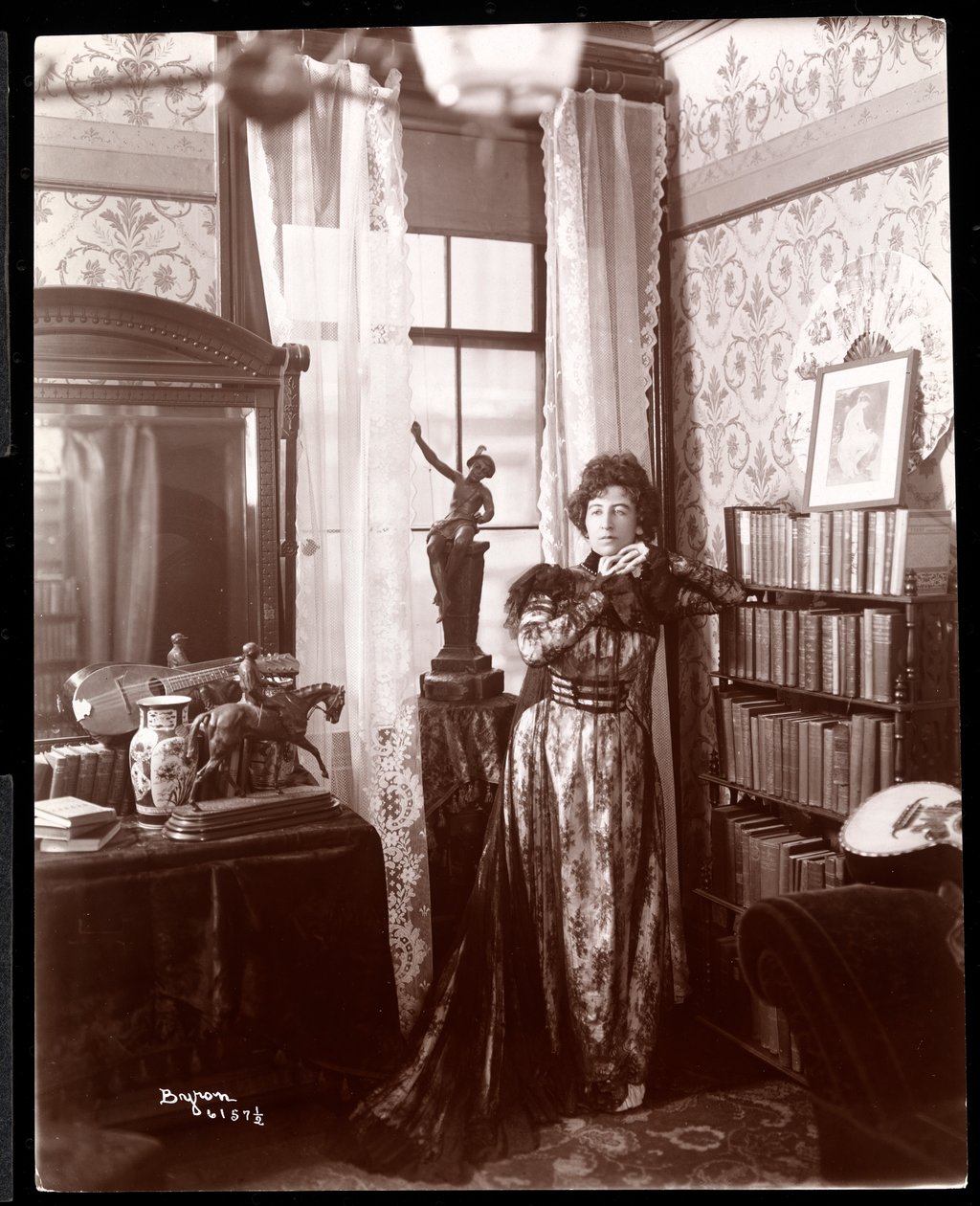 Anita Chartres står i hörnet av ett rum, ca 1898 (silvergelatintryck) av Byron Company