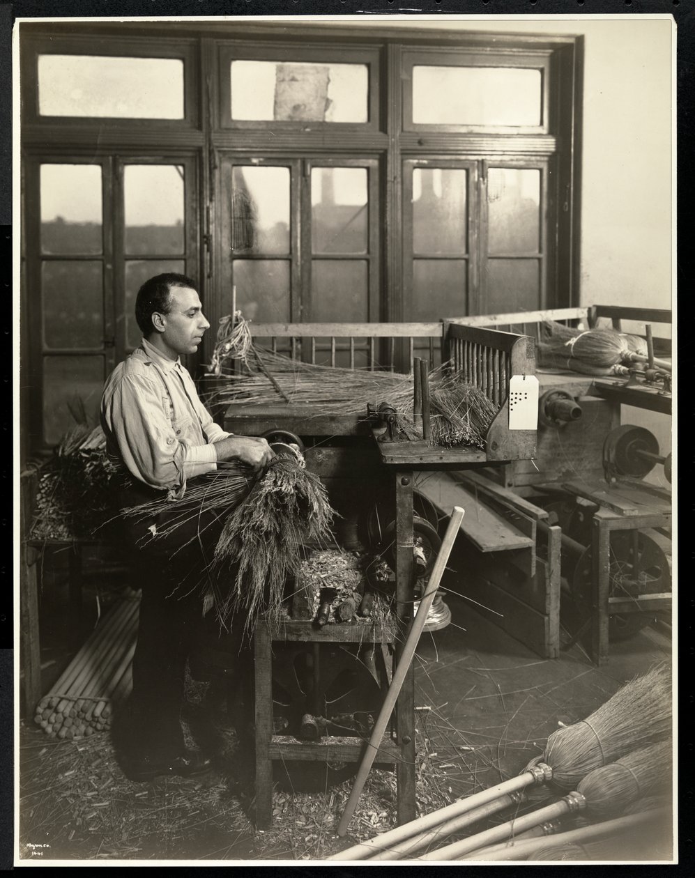 Blind man fäster halm på kvasthandtag i Bourne Memorial Building, New York, 1921 (silvergelatintryck) av Byron Company