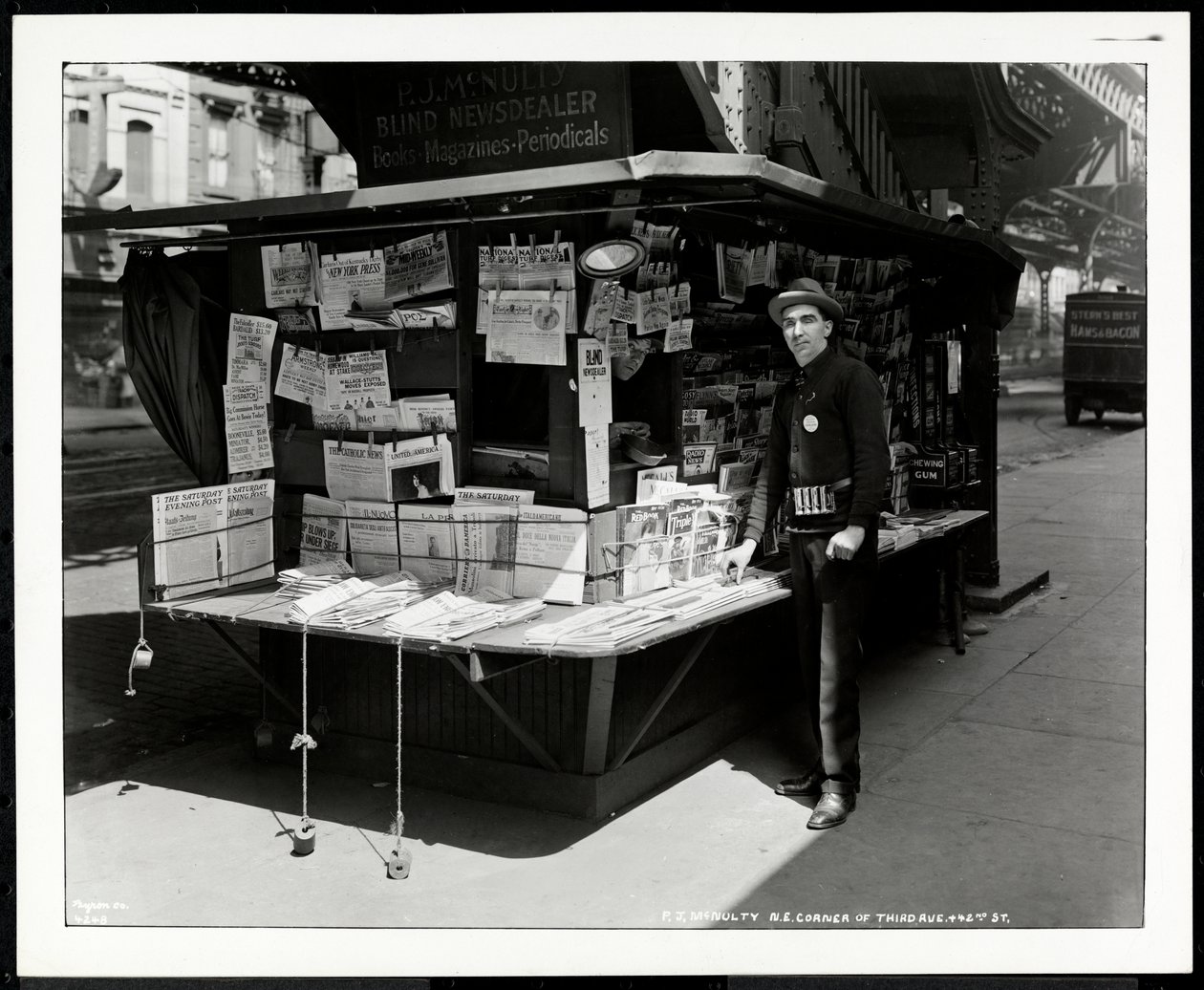 Den blinda nyhetsförsäljaren P.J. McNulty vid sin monter i nordöstra hörnet av 3rd Avenue och 42nd Street, New York, 1926 (silvergelatintryck) av Byron Company