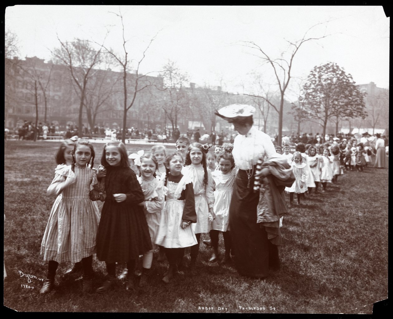 Barn i en lång rad leds av en kvinna på Arbor Day i Tompkins Square Park, New York, 1904 (silvergelatintryck) av Byron Company