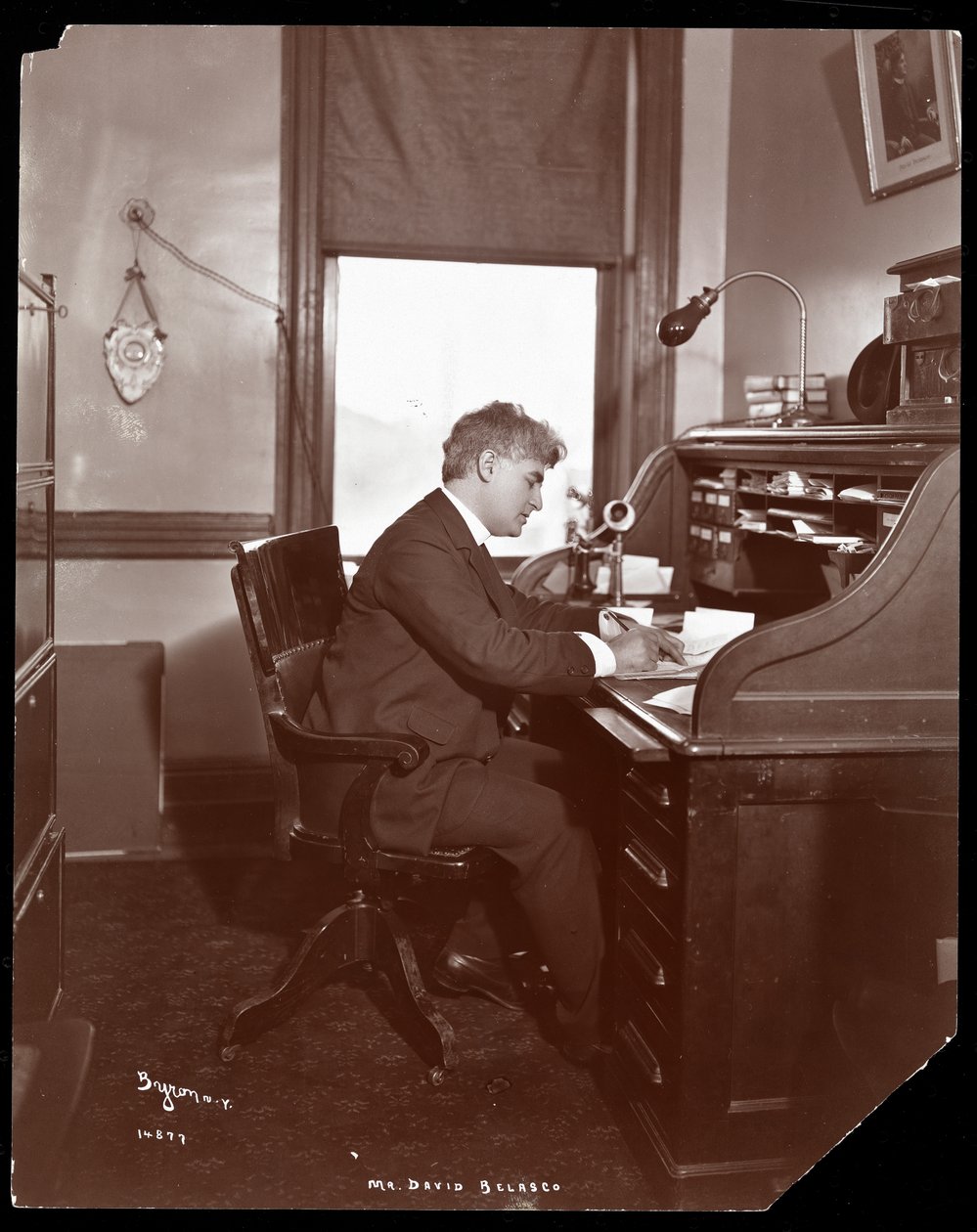 David Belasco skriver vid ett skrivbord i sin teaters kontor, 1902 (silvergelatintryck) av Byron Company