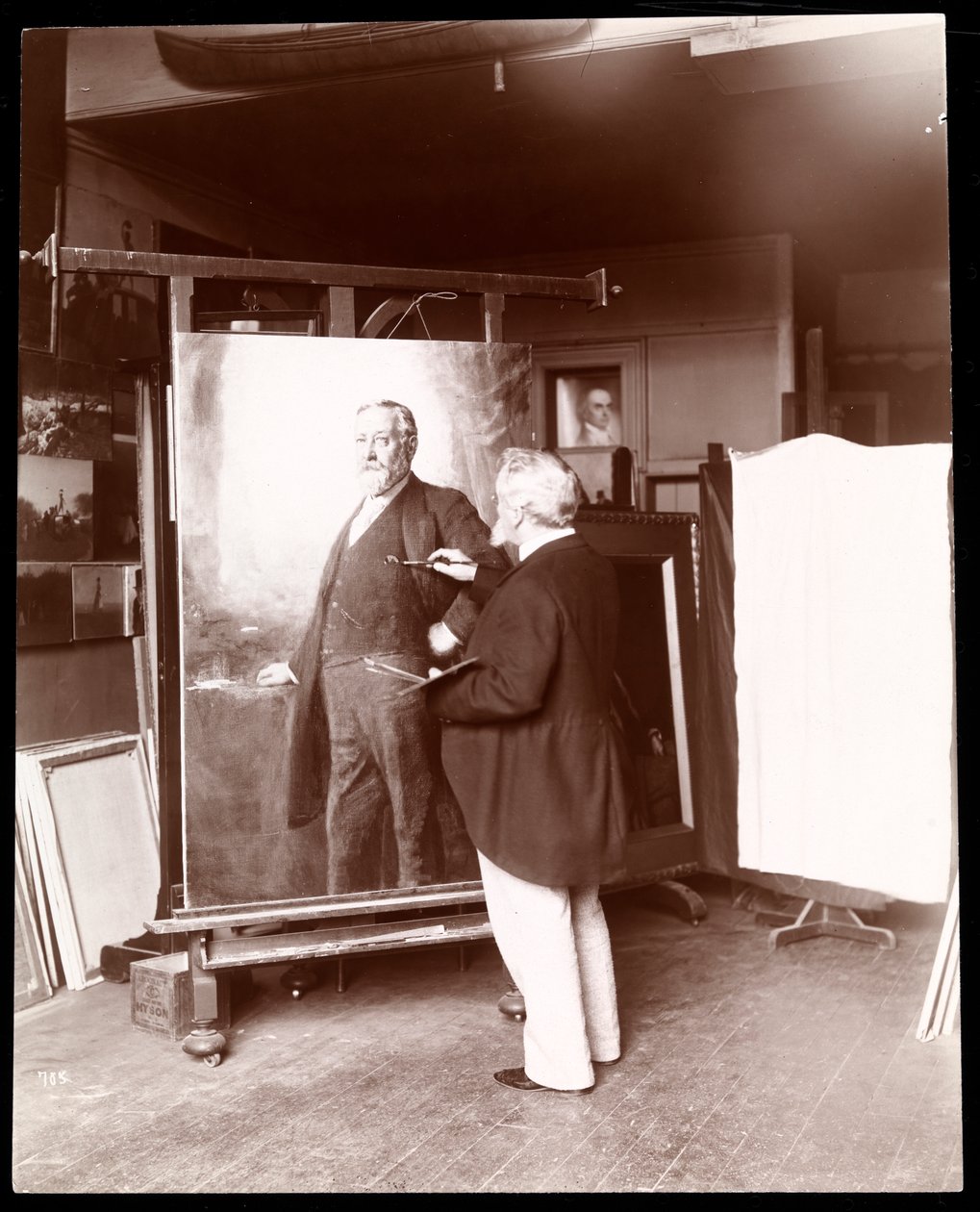Eastman Johnson med pensel i handen arbetar på ett porträtt av president Harrison i sin ateljé, New York, 1895 (silvergelatintryck) av Byron Company