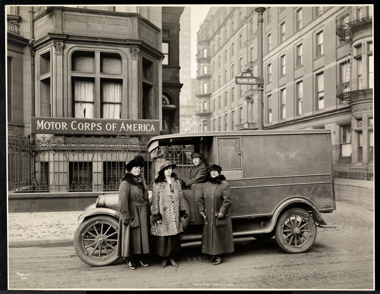 Fyra kvinnor från Motor Corps of America står framför en ambulans (en kvinna i förarsätet) på Park Avenue på 40th Street framför Motor Corps of America-byggnaden, New York, 1920 (s av Byron Company