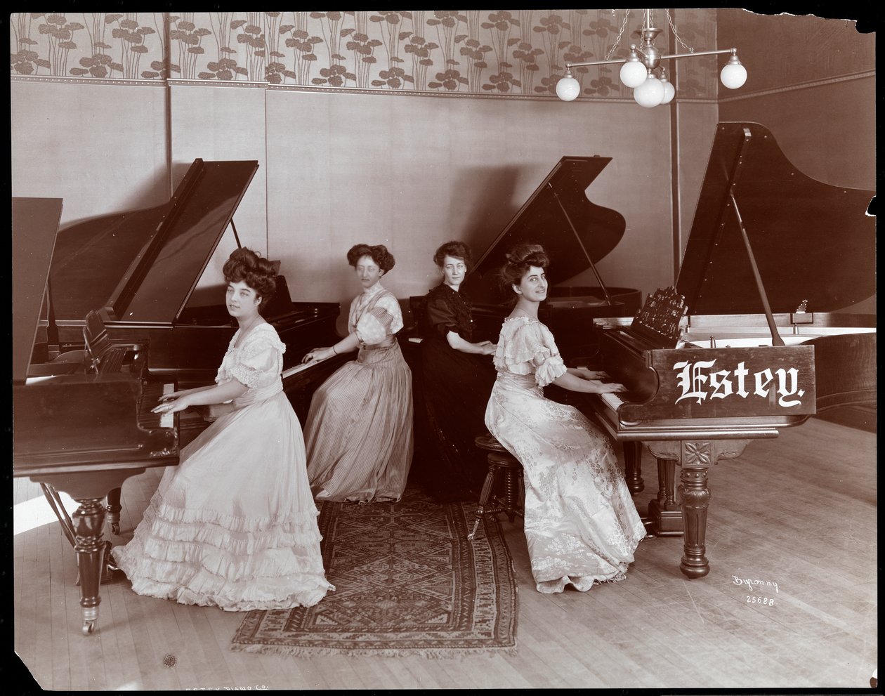 Fyra kvinnor vid pianon på Estey Piano Corporation, 1908 (silvergelatintryck) av Byron Company