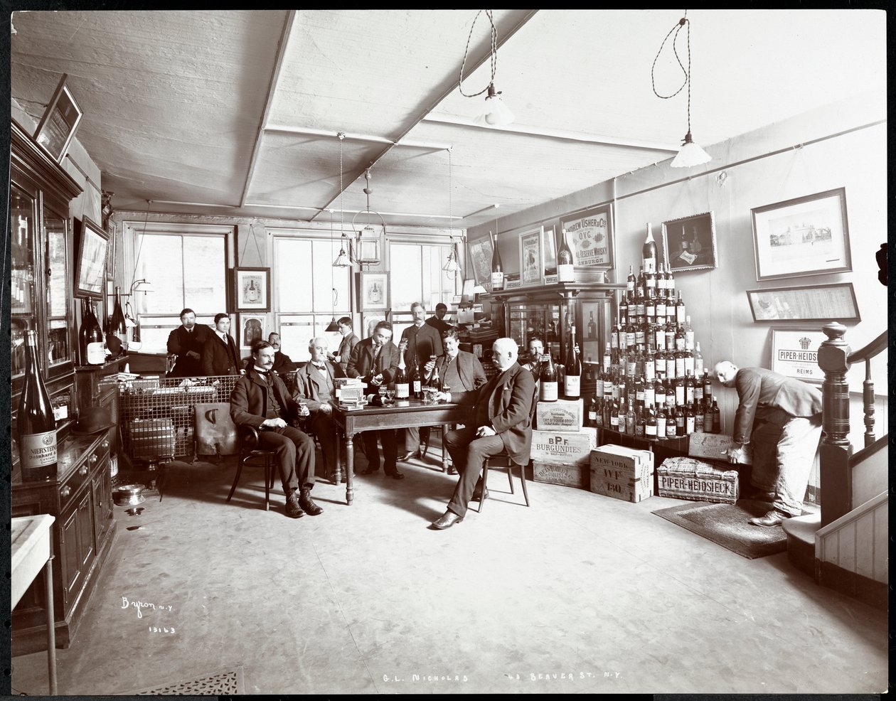 Grupp män som dricker vin hos G.L. Nicholas, vin- och sprithandlare, 43 Beaver Street, New York, 1895 (silvergelatintryck) av Byron Company