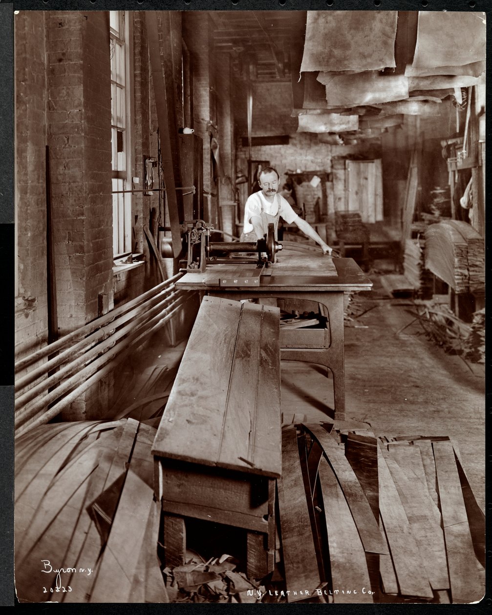 Interiör av en man som arbetar med läder på New York Leather Belting Co. i New York, 1905 (silvergelatintryck). av Byron Company