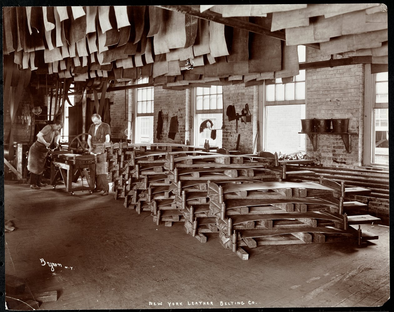 Interiörvy av två män som arbetar med läder på New York Leather Belting Co., New York, 1905 (silvergelatintryck) av Byron Company