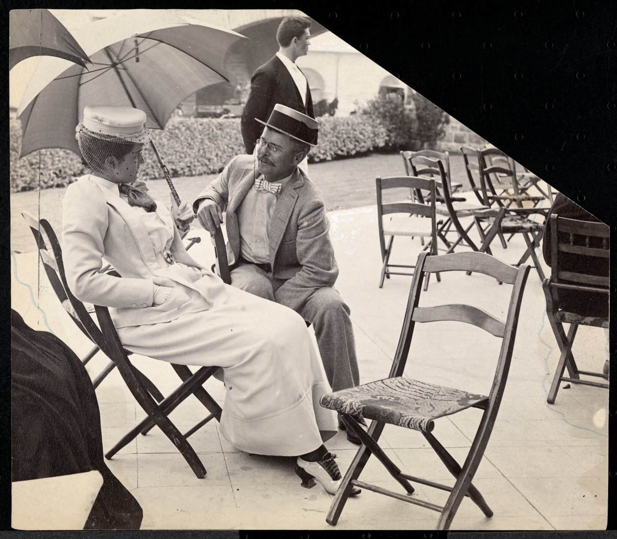 Man och kvinna sitter utanför på hopfällbara stolar med kvinna som håller ett parasoll, Narragansett, Rhode Island, 1891 (silvergelatintryck) av Byron Company