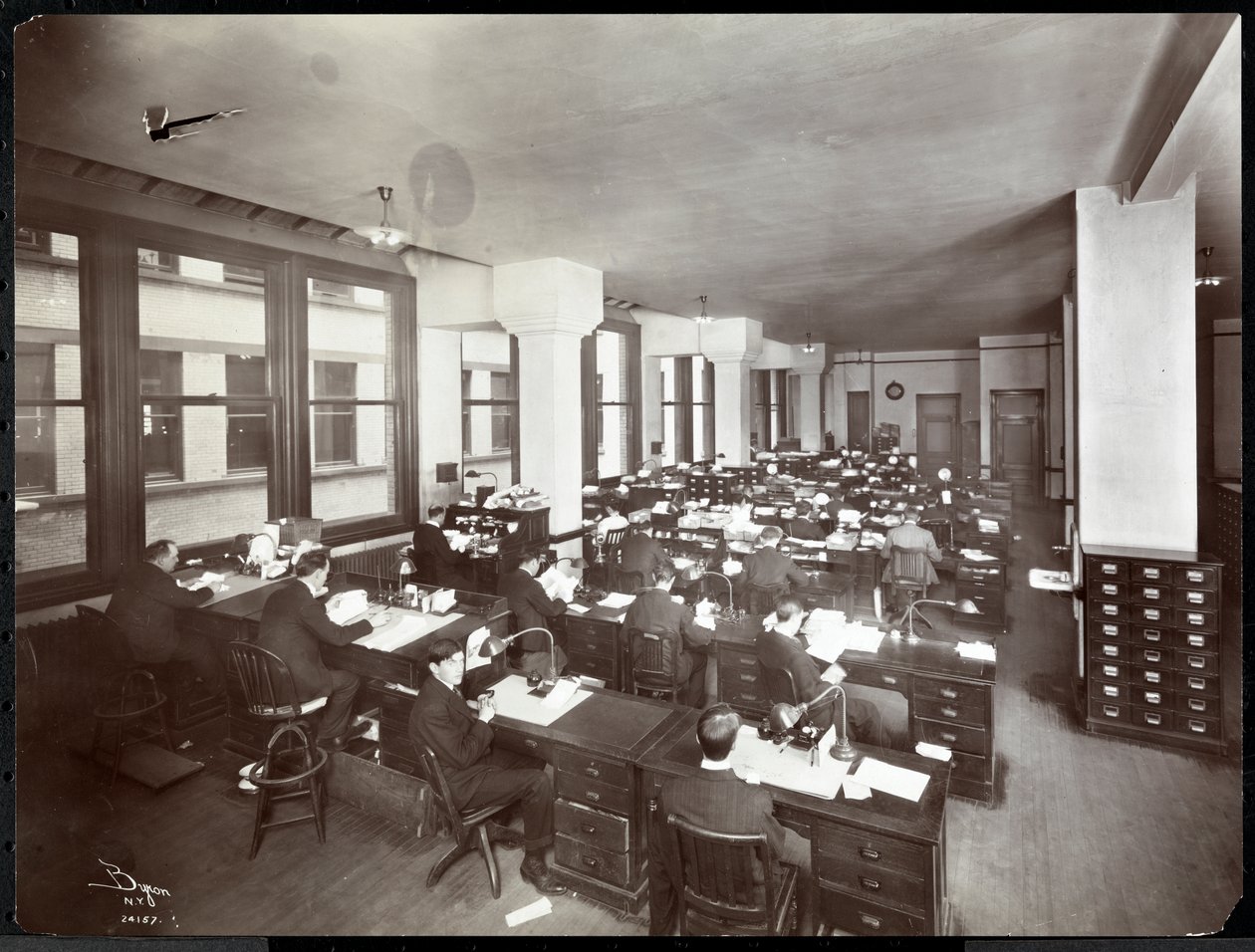 Män och en kvinna som arbetar vid skrivbord på ett kontor på Metropolitan Life Insurance Co. på 23rd Street och Madison Avenue, New York, 1907 (silvergelatintryck) av Byron Company