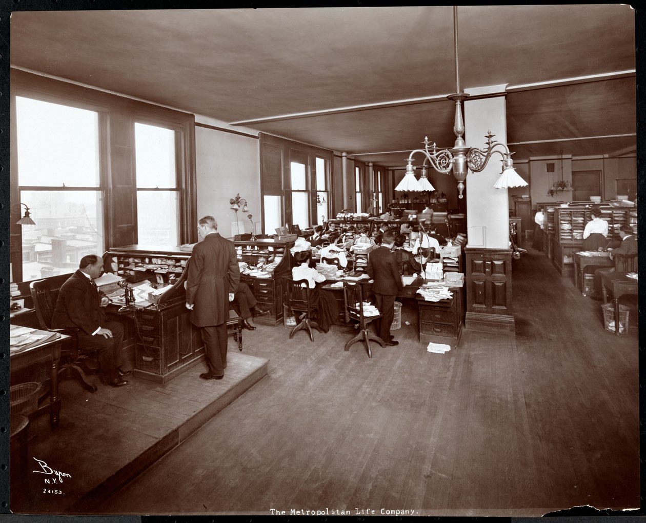 Män och kvinnor som arbetar vid skrivbord på ett kontor på Metropolitan Life Insurance Co. på 23rd Street och Madison Avenue, New York, 1907 (silvergelatintryck) av Byron Company