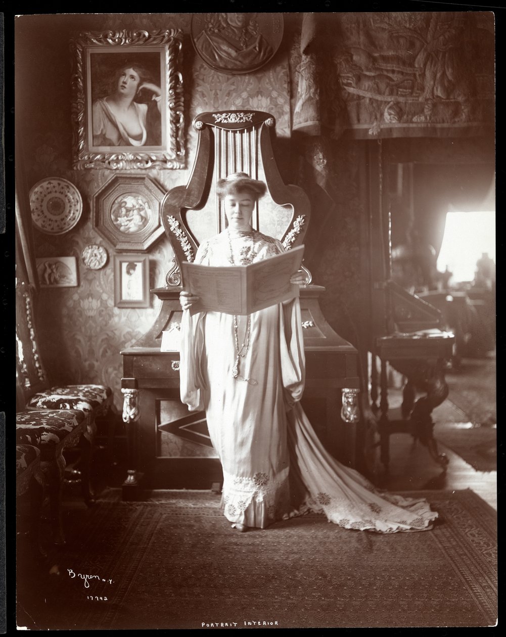 Porträtt av Mrs. I. M. Clark stående med en öppen bok, 1904 (silvergelatintryck) av Byron Company