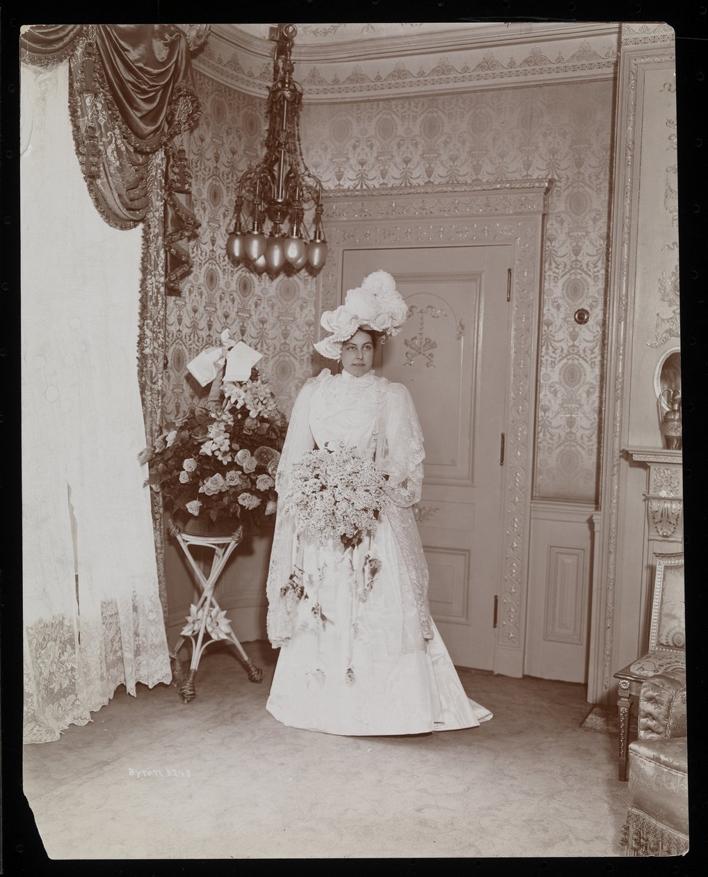 Porträtt av mrs Taylor från "Rider and Driver" stående poserad i sin bröllopsklänning, New York, 1896-8 (silvergelatintryck) av Byron Company