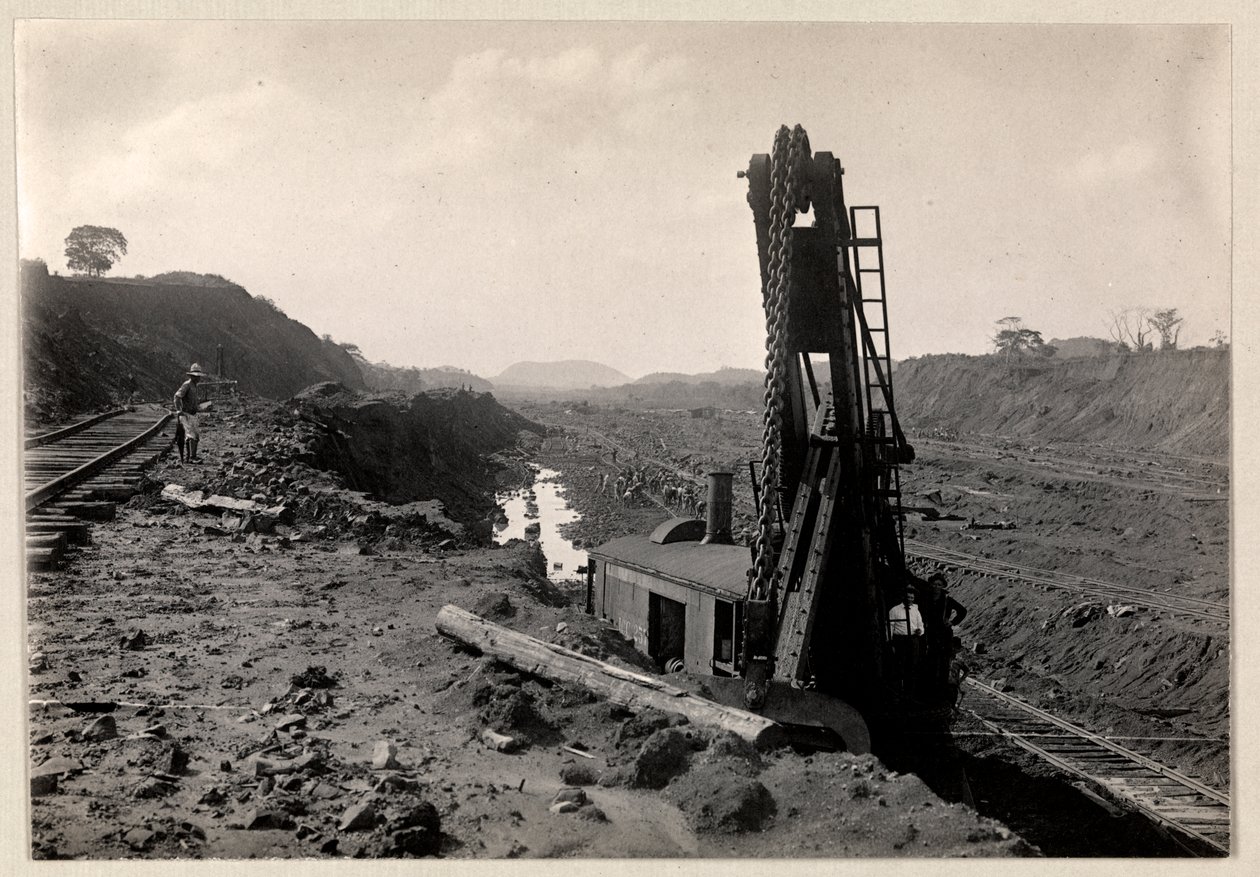 Vy över arbetare som gräver Panamakanalen med järnvägsspår genom ett dike och någon sorts grävmaskin i förgrunden, 1912 eller 1913 (silvergelatintryck) av Byron Company
