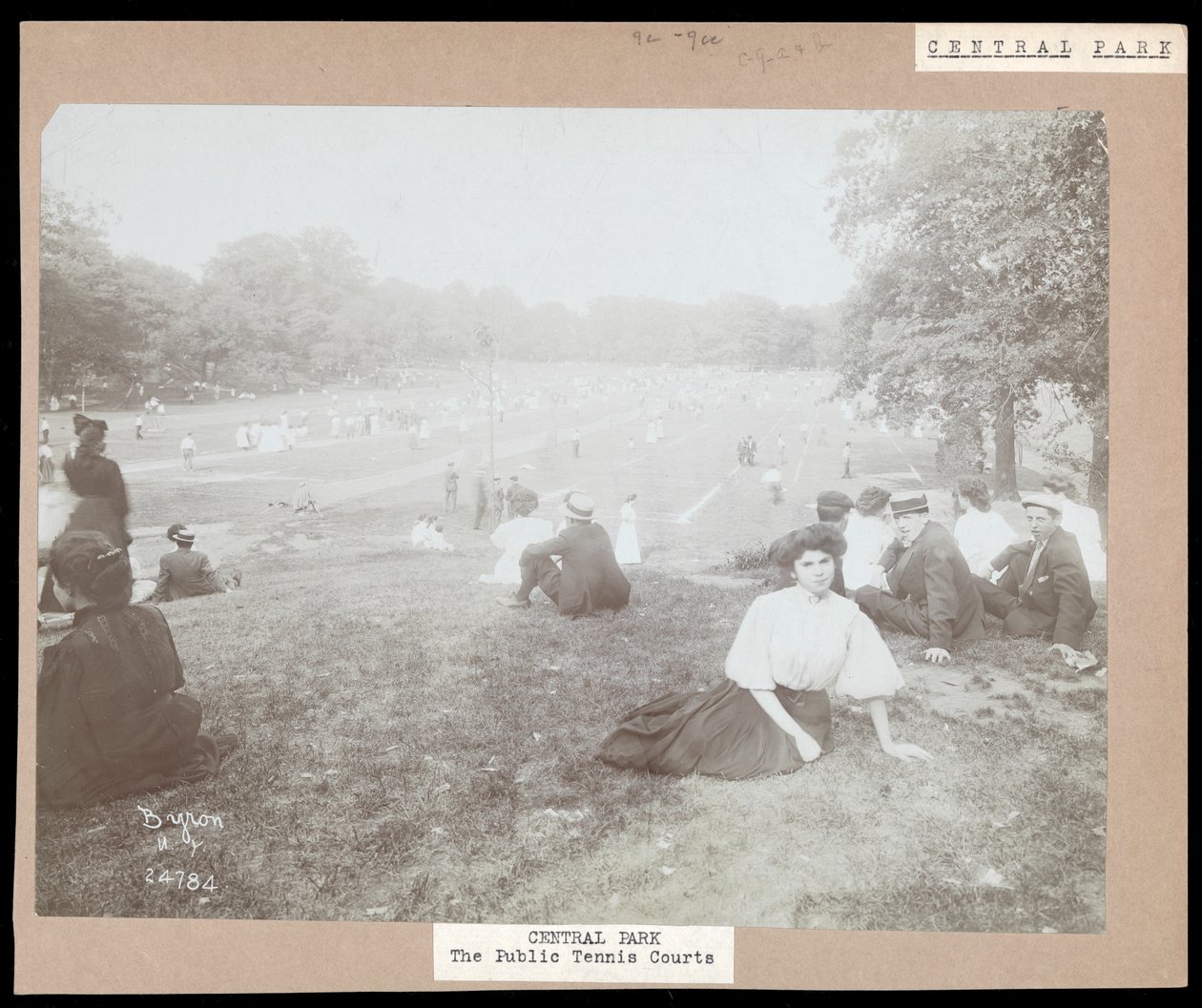 Vy över män och kvinnor som sitter på gräs och tittar på grästennis i Central Park, New York, ca 1917 (silvergelatintryck) av Byron Company