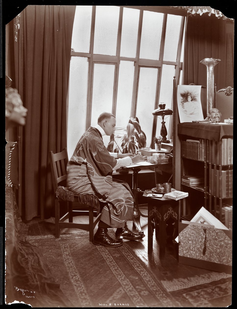 Will R. Barnes i en mantel, sittande vid sitt skrivbord i sin studio, 1903 (silvergelatintryck) av Byron Company