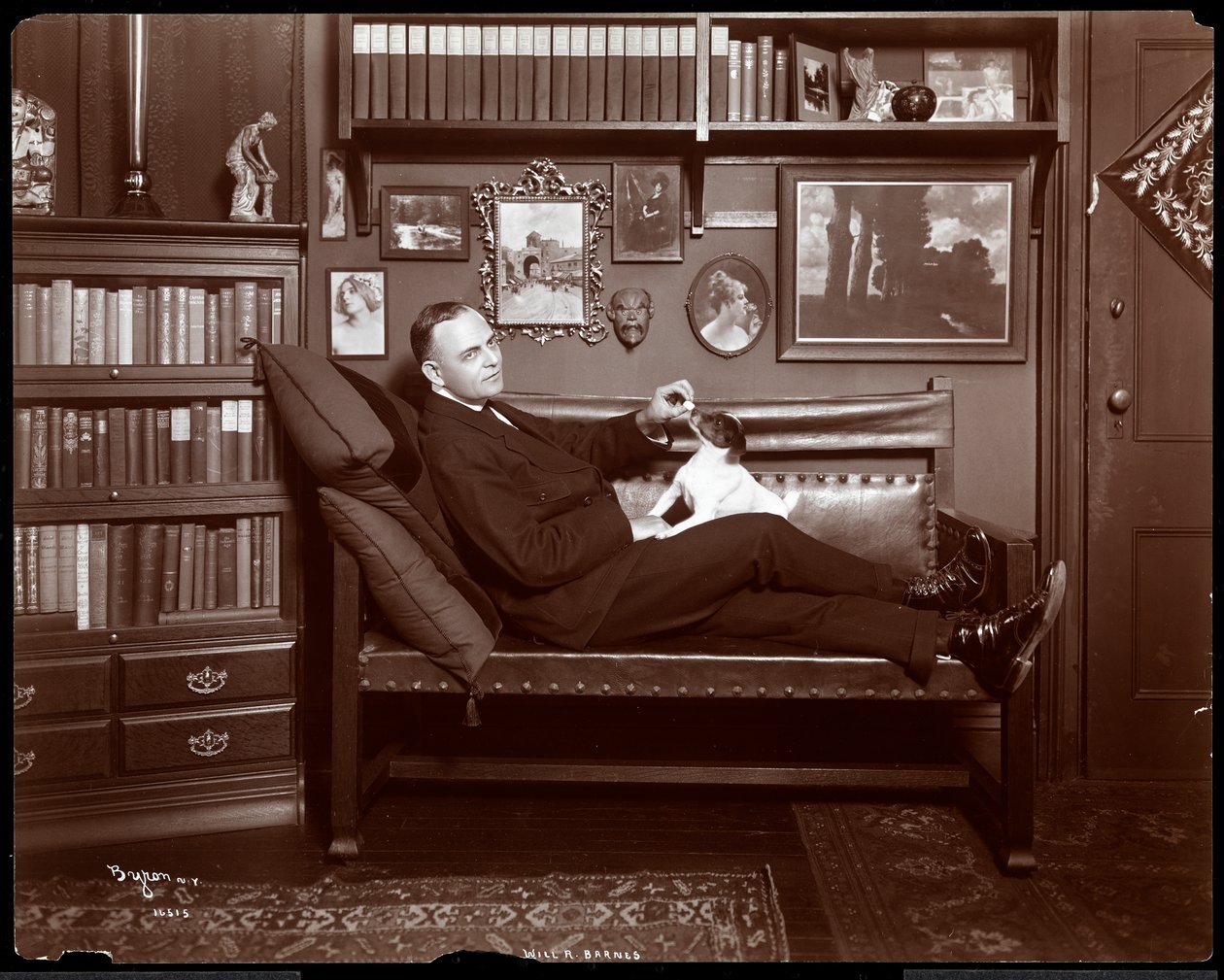 Will R. Barnes lutade sig tillbaka på en soffa med en hund i hans biblioteksstudio, 1903 (silvergelatintryck) av Byron Company