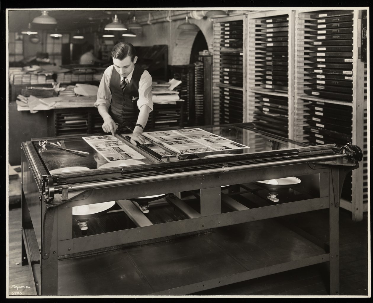 Arbetar på en layout vid ett ljusbord på Unz und Co., 24 Beaver Street, New York, 1932 (silvergelatinprint). av Byron Company