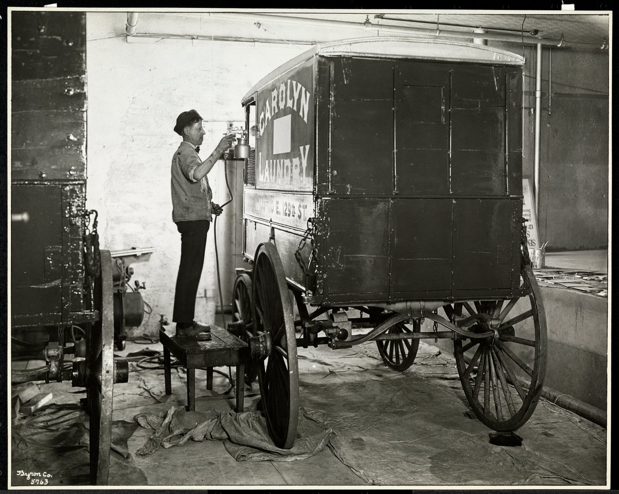 En man sprayar en leveransvagn från Carolyn Laundry på 111 East 128th Street, East Harlem, New York, 1929 (silvergelatintryck). av Byron Company