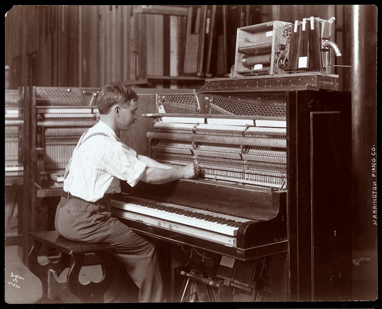 En man som arbetar i Harrington Piano Co.-fabriken, 1907 (silvergelatintryck) av Byron Company