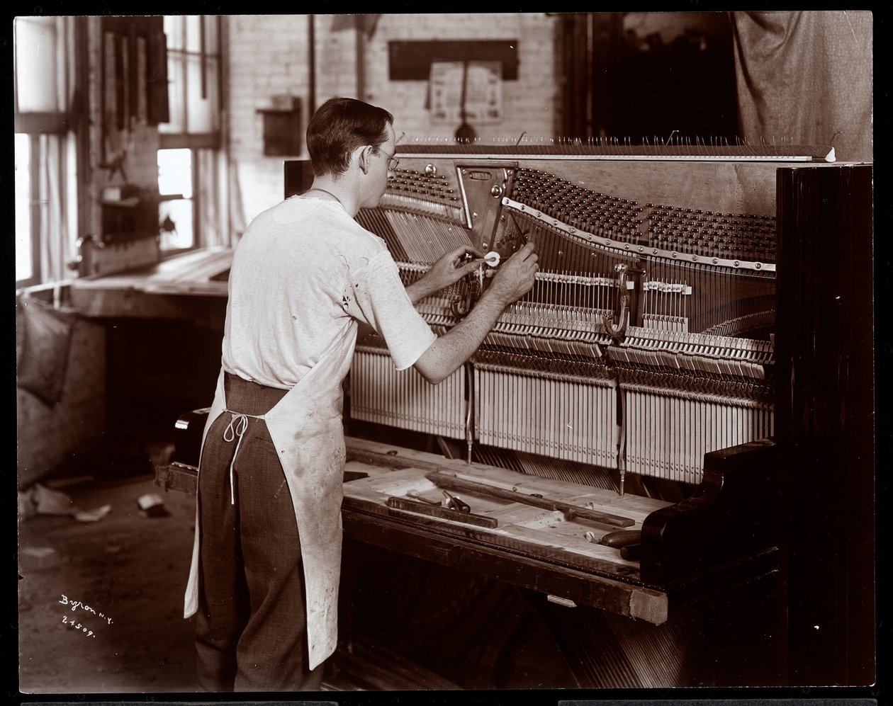 En man arbetar i Hardman, Peck und Co. pianofabrik, New York, 1907 (silvergelatintryck) av Byron Company