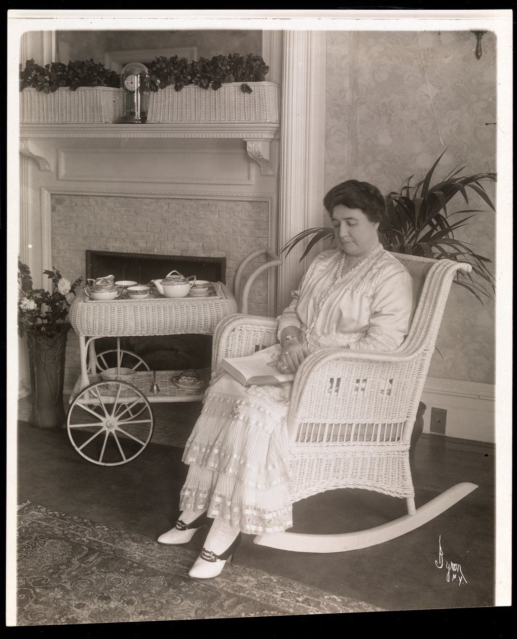 Mrs. Howard satt med en bok i en gungstol i sitt hem på 200, 5th Avenue, New York, 1915-6 (silvergelatintryck) av Byron Company
