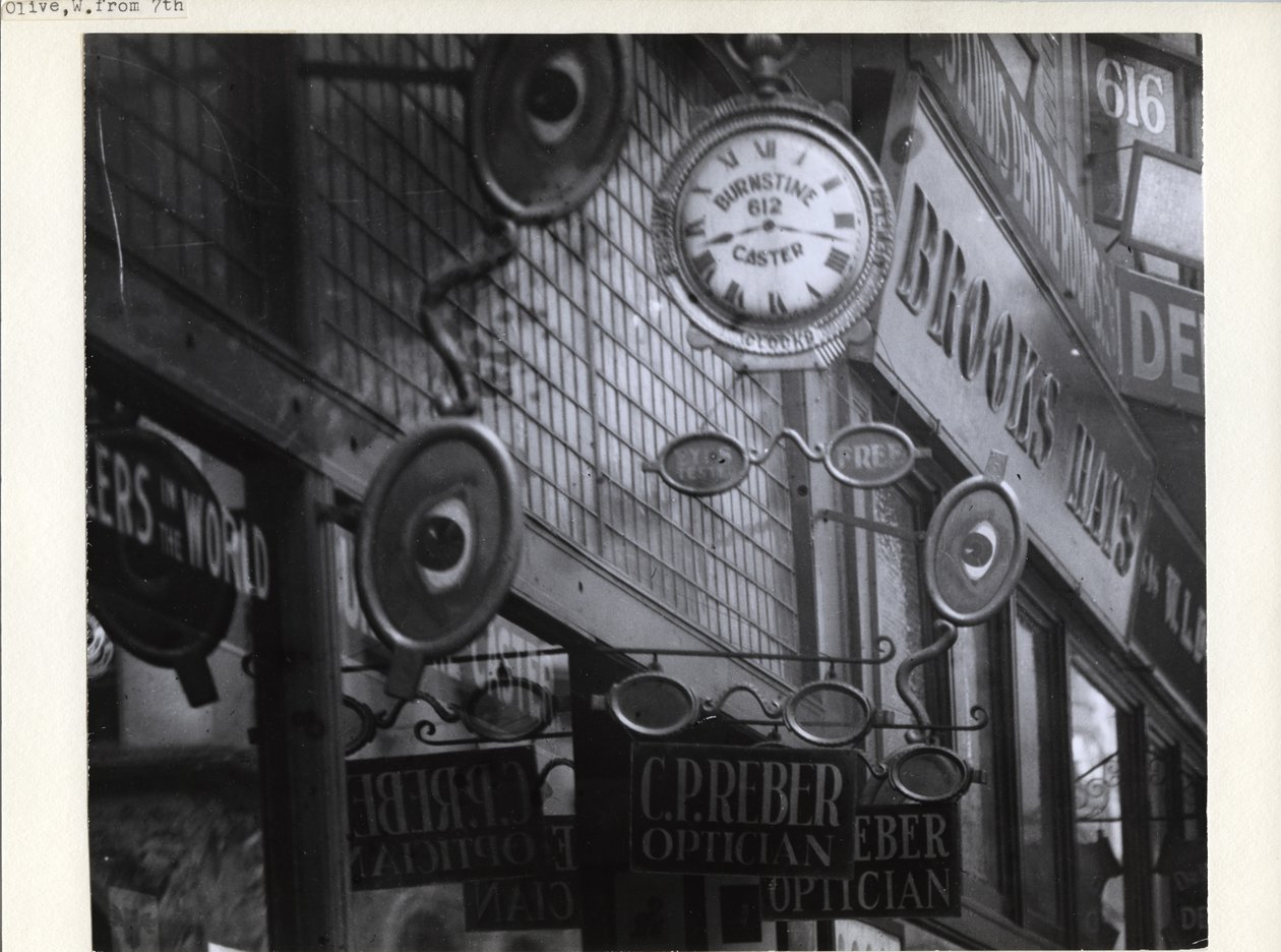 Signs for C.P. Reber Optician, Burnstine Caster Clocks, and Brooks Hats along their 612-614 Olive Street store fronts av Charles Clement Holt