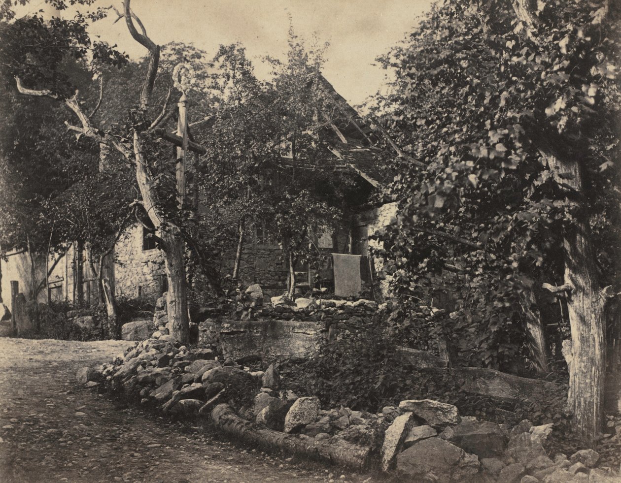 Lantlig scen med stenbyggnad och kors, ca. 1857. av Charles Fortunat Paul Casimir Perier