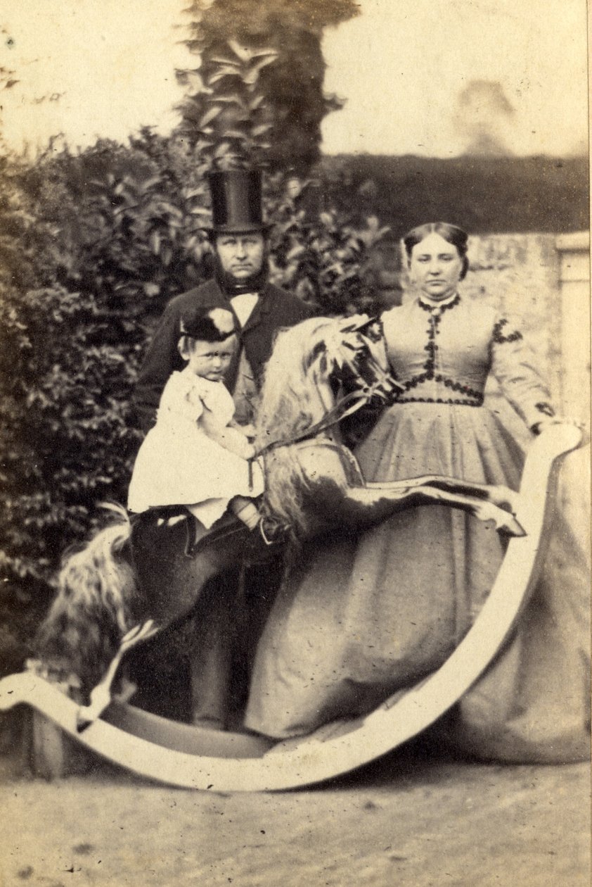 Ung flicka på en stor gunghäst med en man och en kvinna som står, 1860-talet (albumenprint) av Cruttenden