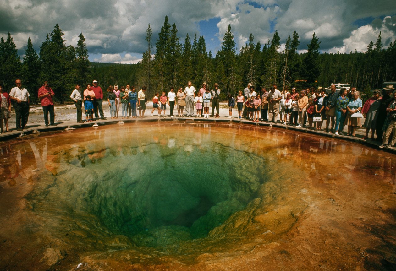Parkbesökare samlas runt en blågrön, blomformad termisk pool. Yellowstone nationalpark... av Dean Conger