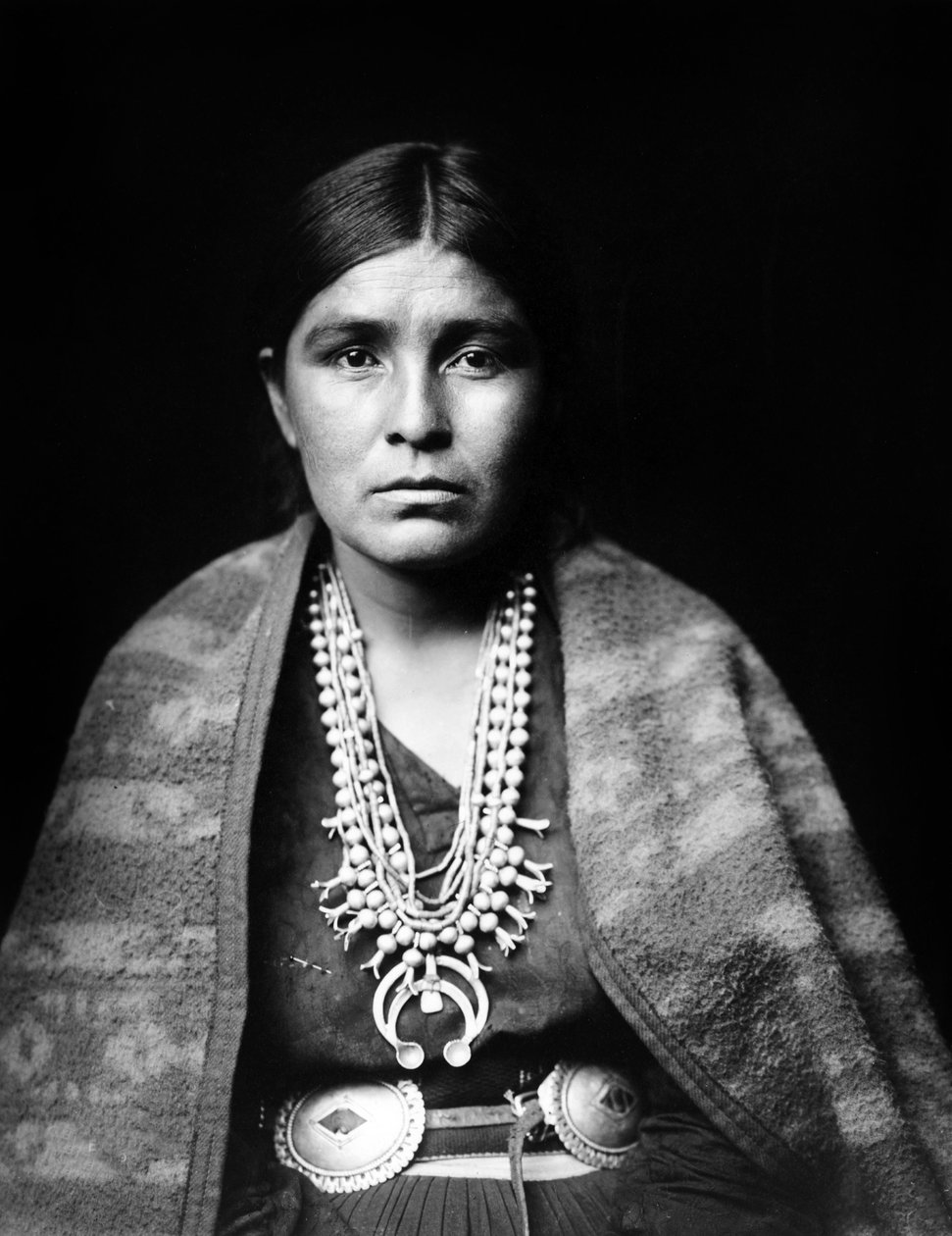 Navajokvinna som bär silverhalsband med squashblommor, conchobälte, filt draperad över axlarna, ca. 1904, foto Edward S. Curtis av Edward Sheriff Curtis