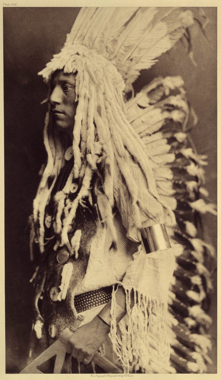 Gammal person, Piegan. Unga män missar inte något tillfälle av offentliga festligheter för att ta på sig kläderna till sin krigarfar. Foto taget från volym 6 av uppslagsverket publicerat av Edward S. Curtis (1868-1952) om indianerna i Nordamerika, med en f av Edward Sheriff Curtis