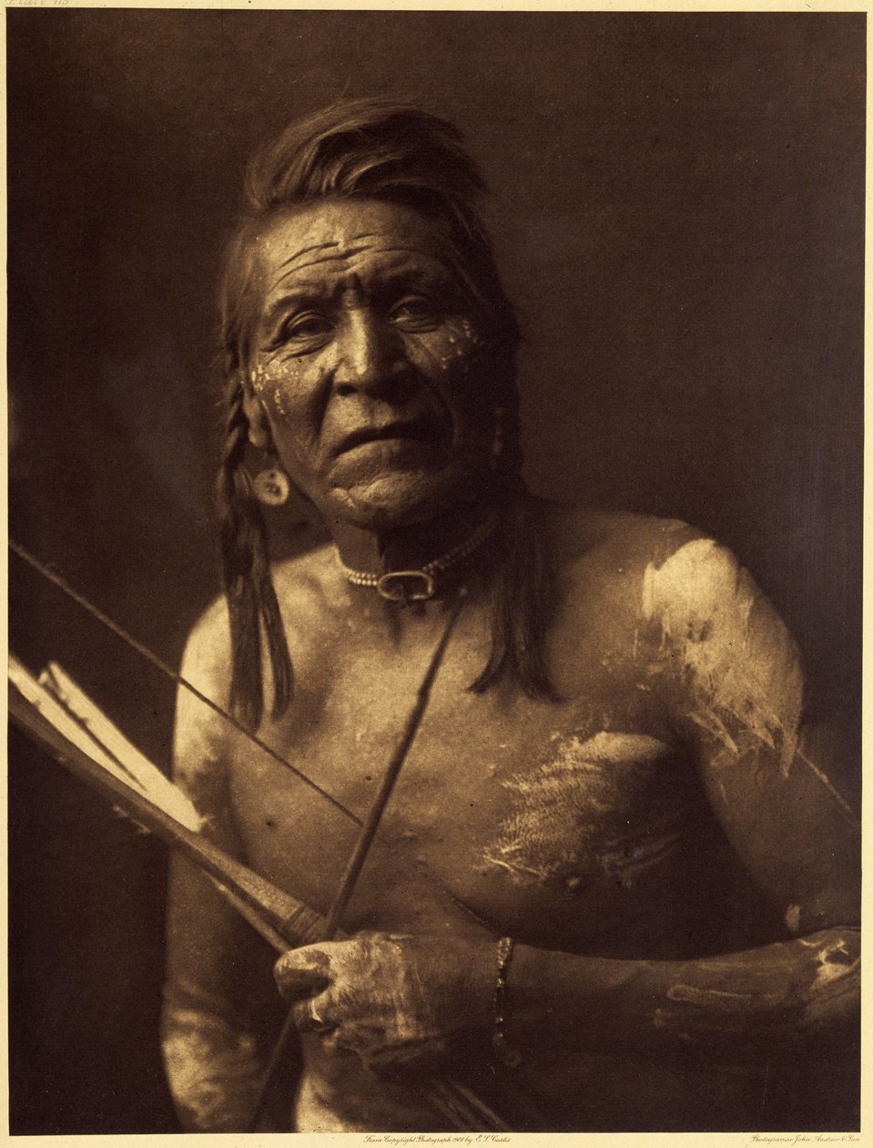 Two Leggings, Apsaroke, gjorde omkring 1848. Hans visioner gav honom inga stora krafter, och han släpptes in i ett hemligt tobakssällskap av Bull Goes Hunting, som gav honom sin amulett gjord av ett fossil eller en grovt sulfatsten i form av en dubbelsidig av Edward Sheriff Curtis